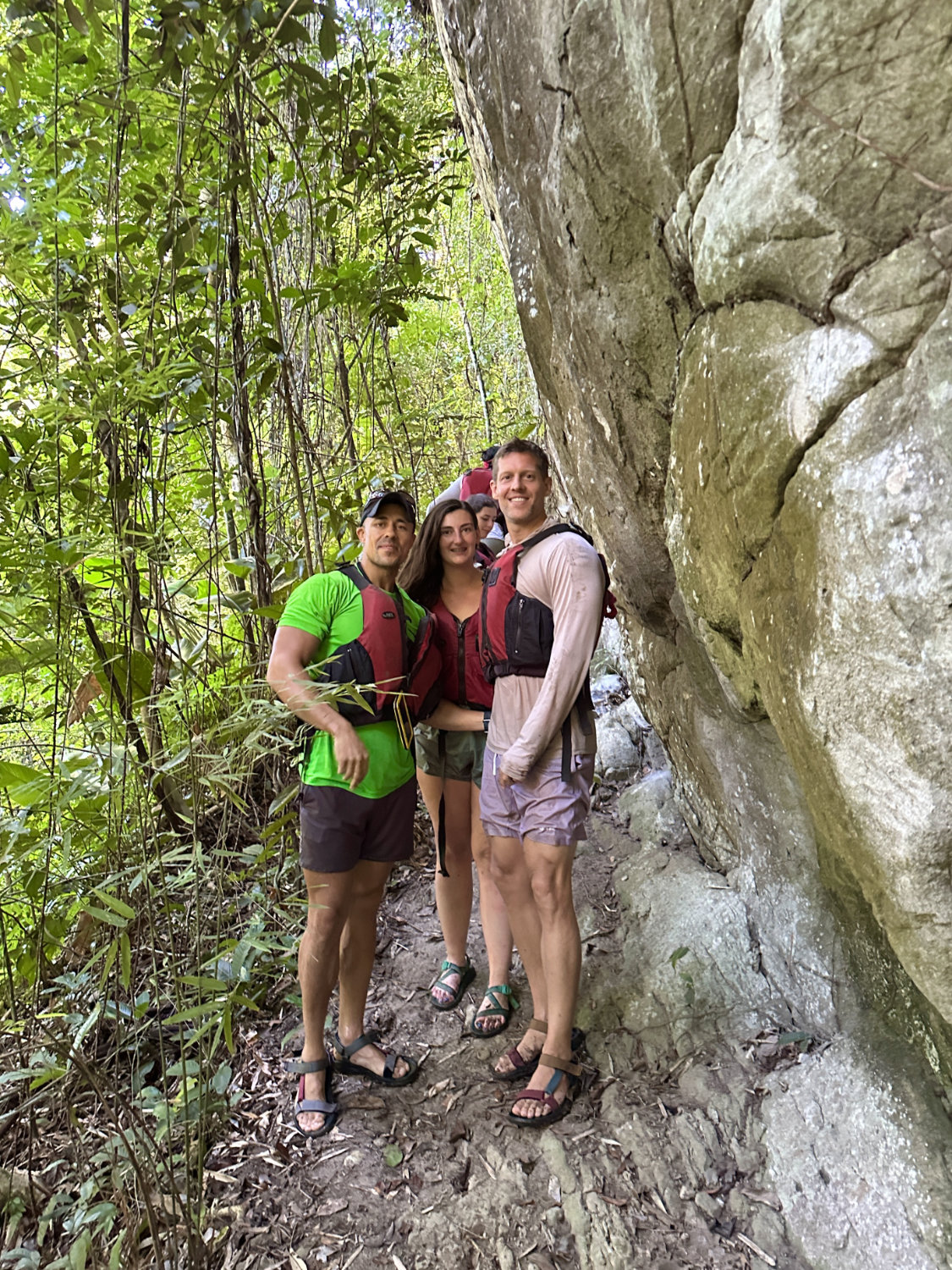 Coop, Debbie and Mark standing next to rock with Mayan face carvings