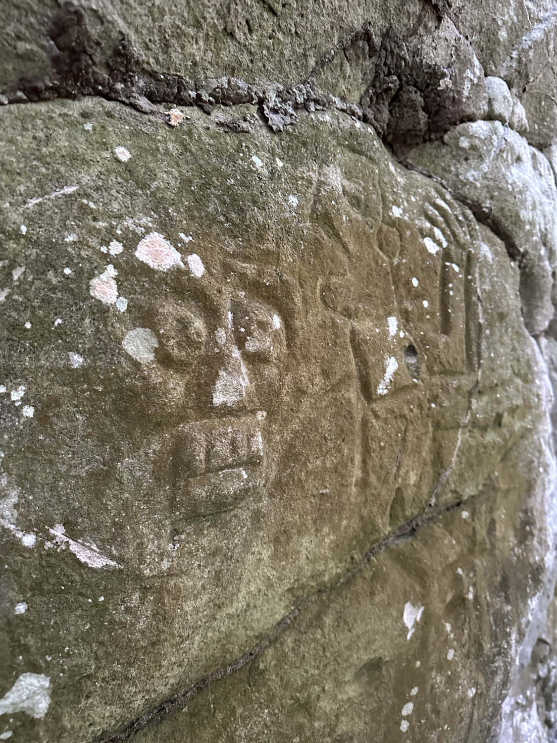 Mayan face and monkey carving in rock face