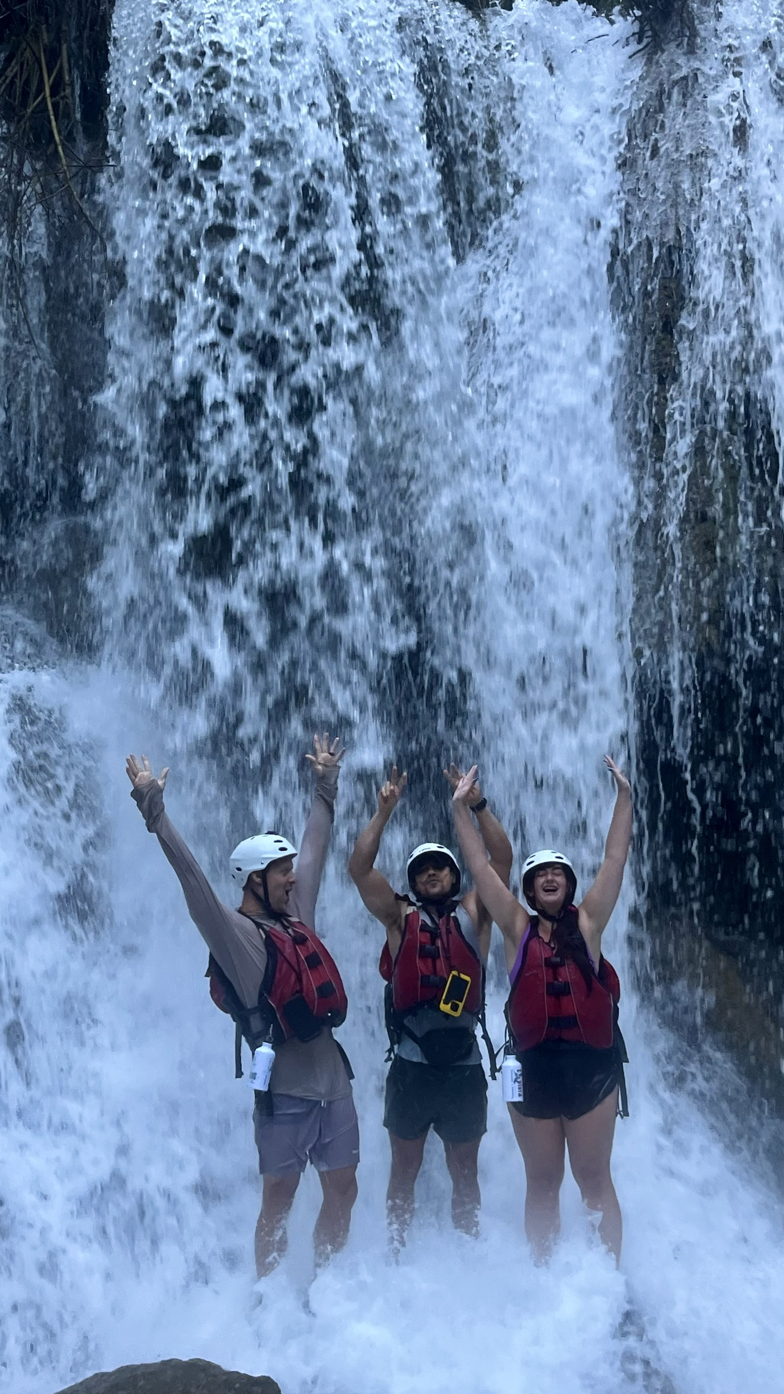 Mark, Coop, and Debbie hands up in waterfall